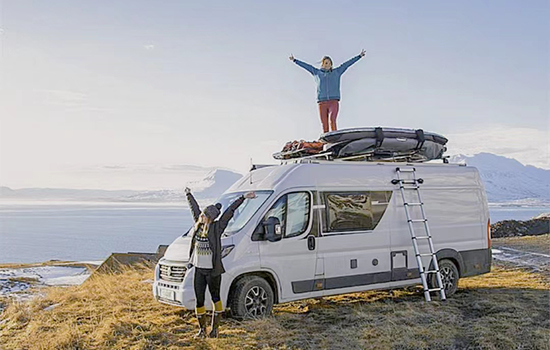 one girl is standing on the top of rv and waving her hands after she climbing with a telescoping roof top tent ladder