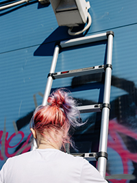 a pink hair girl is standing on a telescopic ladder