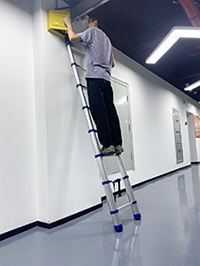 a man is checking the electric box with aluminium telescopic ladder