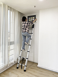 a girl is hanging a painting with a en131 telescopic ladder