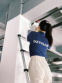 a girl standing on a telescopic extension ladder to install a camera